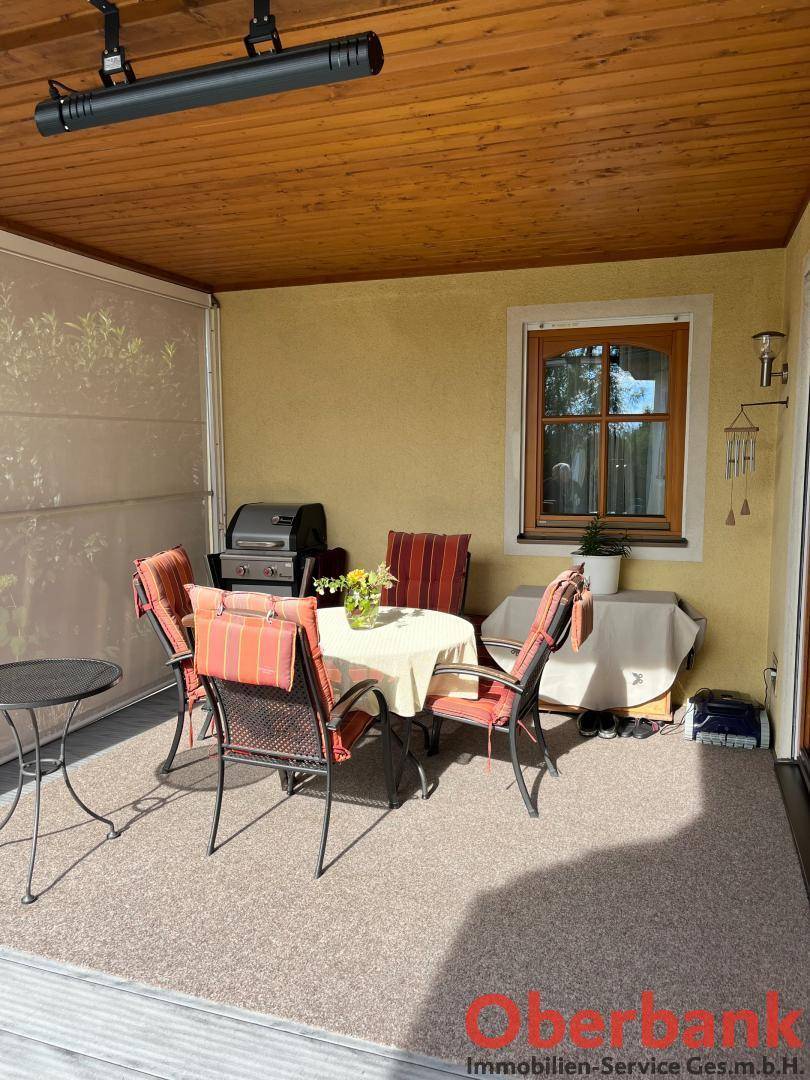 Überdachte Terrasse mit Holzdach, Esstisch und Stühlen, ideal für Mahlzeiten im Freien.