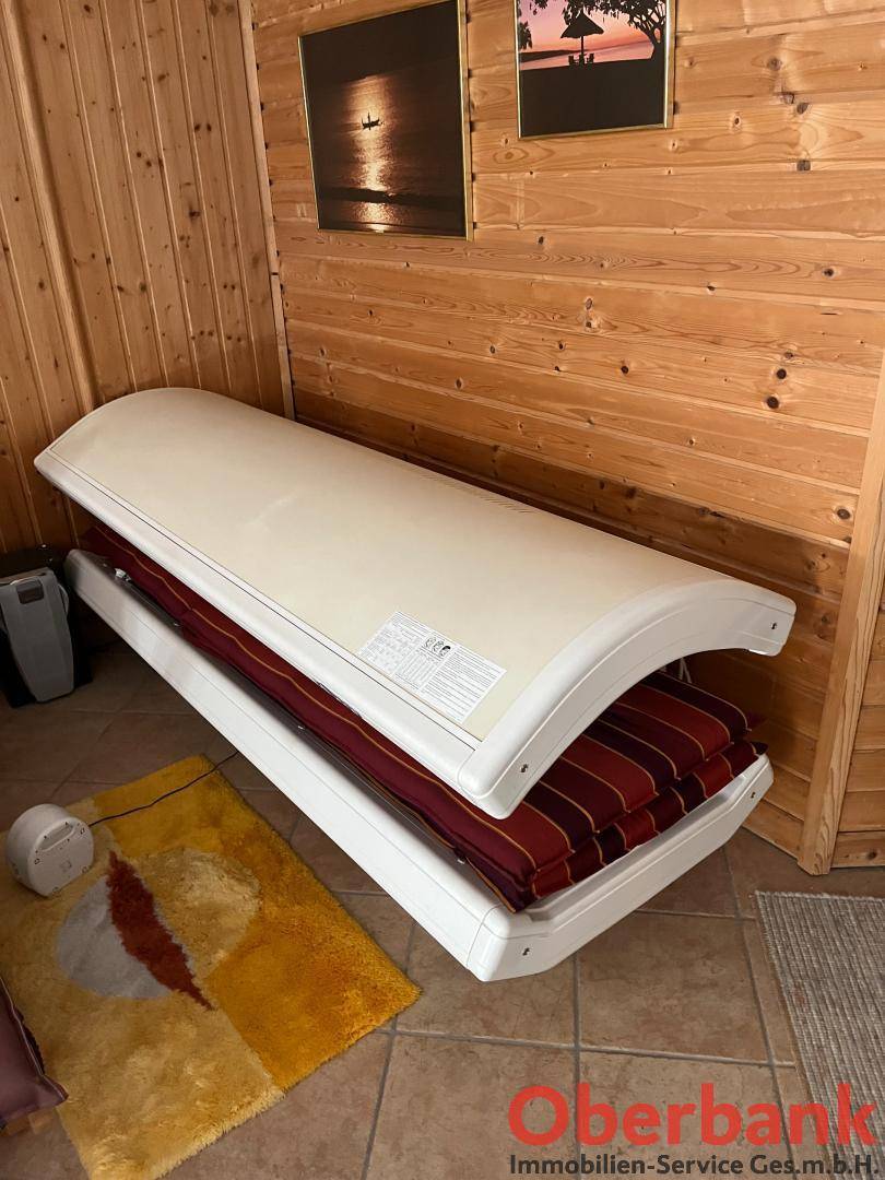 Solarium in einem Raum mit Holzverkleidung und Fliesenboden für Bräunungssitzungen.