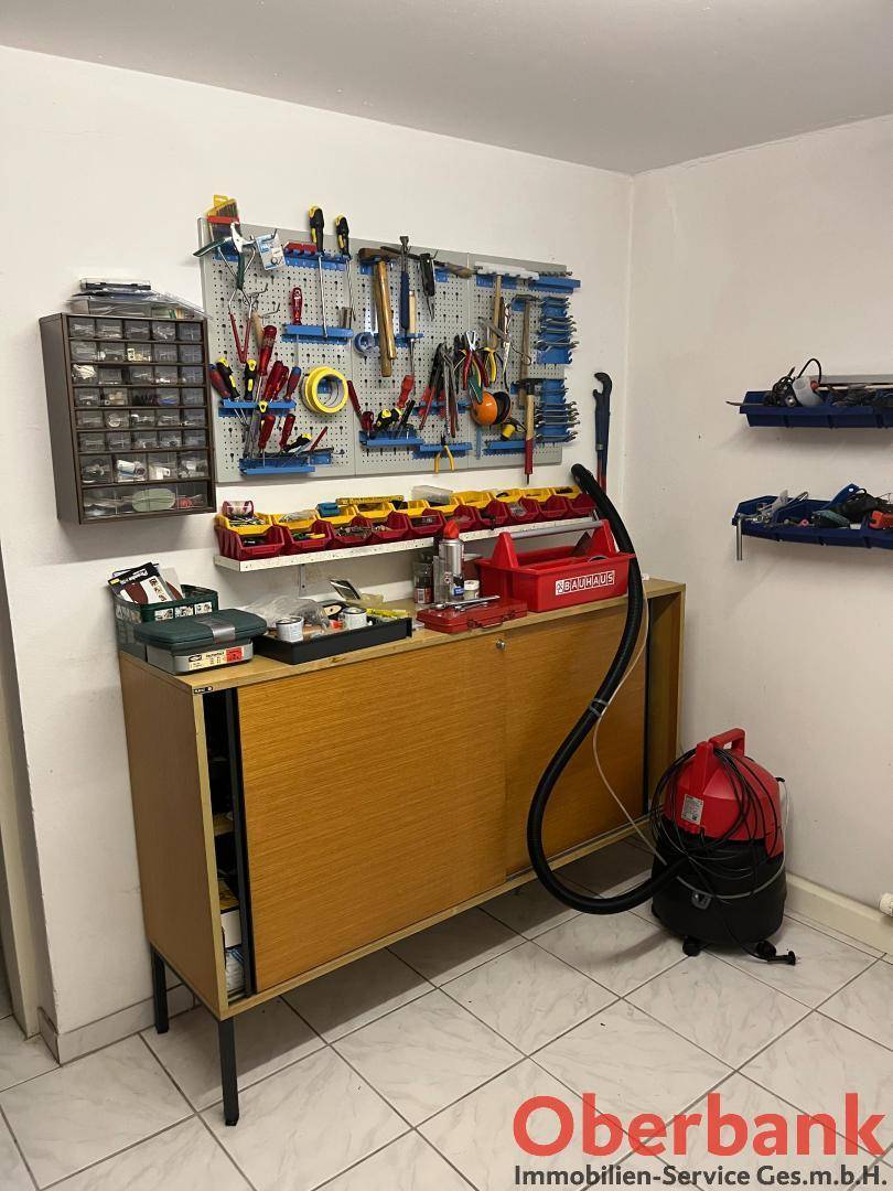 Gut organisierter Werkstattbereich mit Werkzeugwand, Schrank und Staubsauger.