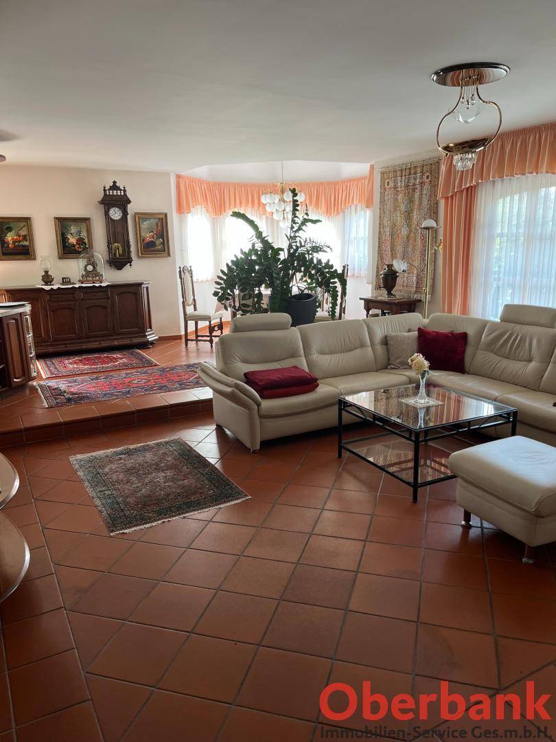 Geräumiges Wohnzimmer mit beigen Ledersofas, Terrakottafliesen und traditionellen Möbeln.
