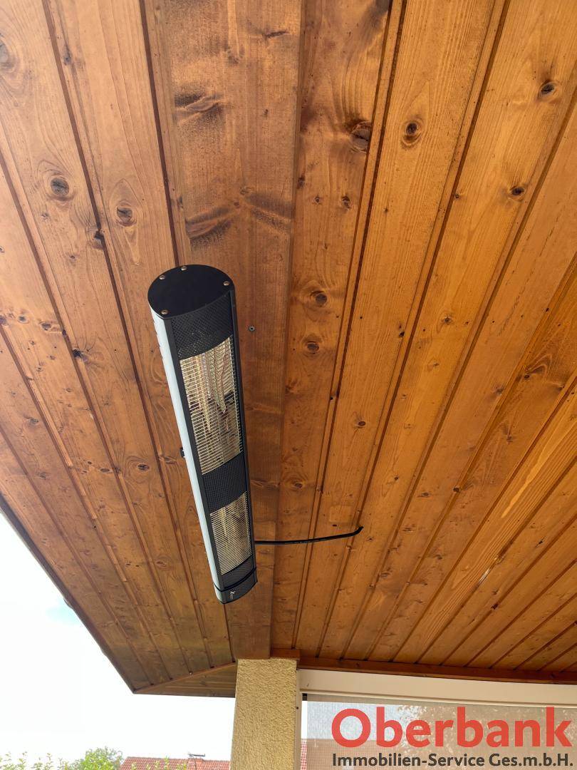 Infrarot-Heizstrahler an der Holzdecke der überdachten Terrasse für kühle Abende.