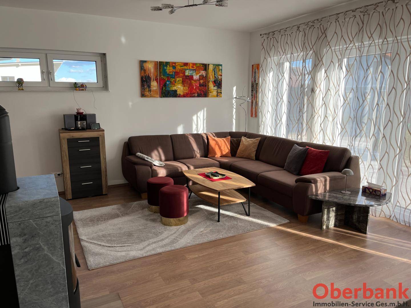 Gemütliches Wohnzimmer mit großem Ecksofa, Holzboden und Kaminofen.