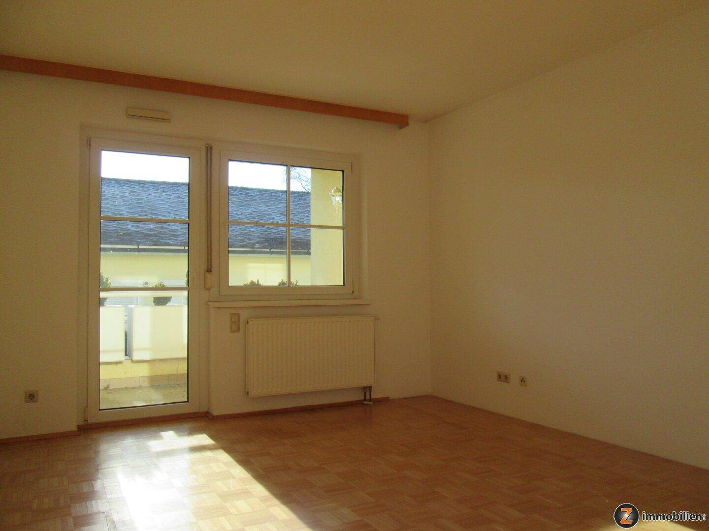 Lichtdurchfluteter Raum mit Parkettboden und direktem Balkonzugang.