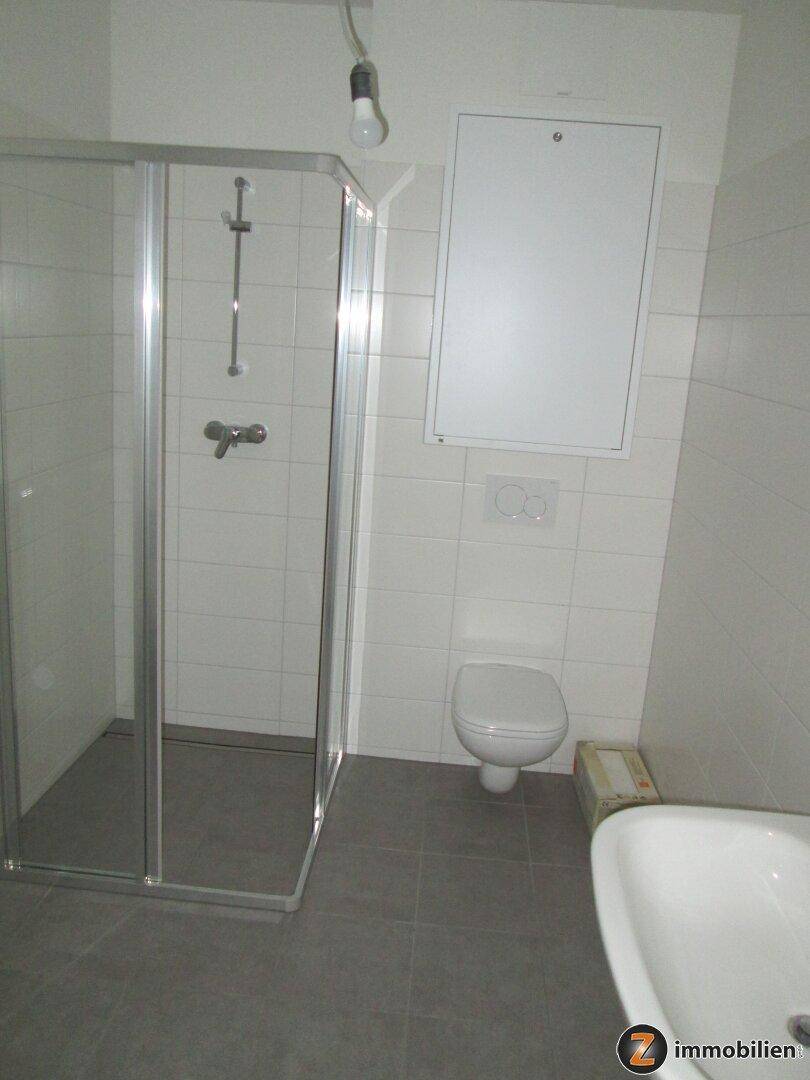 Modernes Badezimmer mit Duschkabine, wandhängendem WC und Waschbecken.
