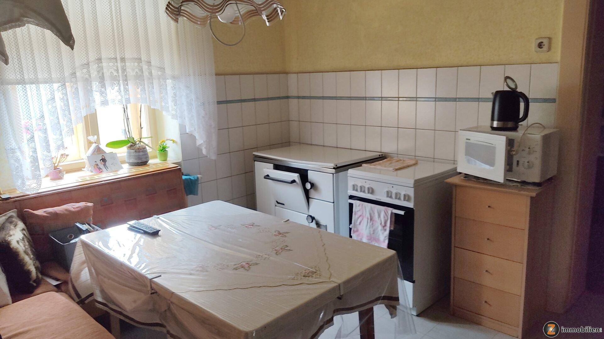 Traditionelle Küche mit weiß gefliesten Wänden, einem Esstisch und älteren Küchengeräten.