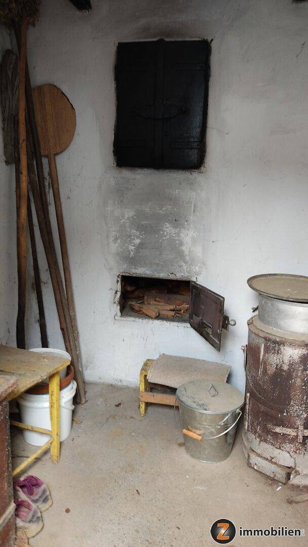 Rustikaler Raum mit einem traditionellen Ofen oder Kamin und Holzutensilien.