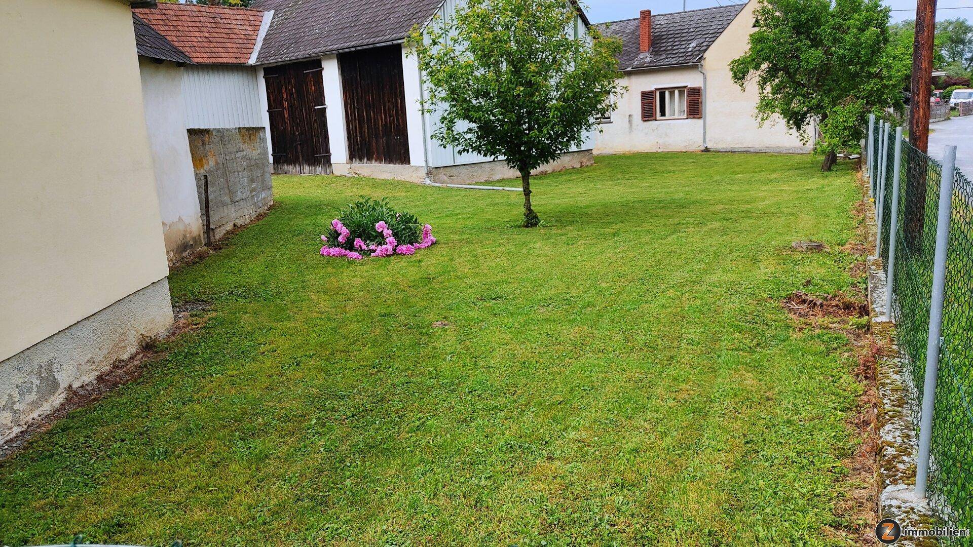 Gepflegte Rasenfläche im Gartenbereich zwischen den Gebäuden mit blühenden Pflanzen.