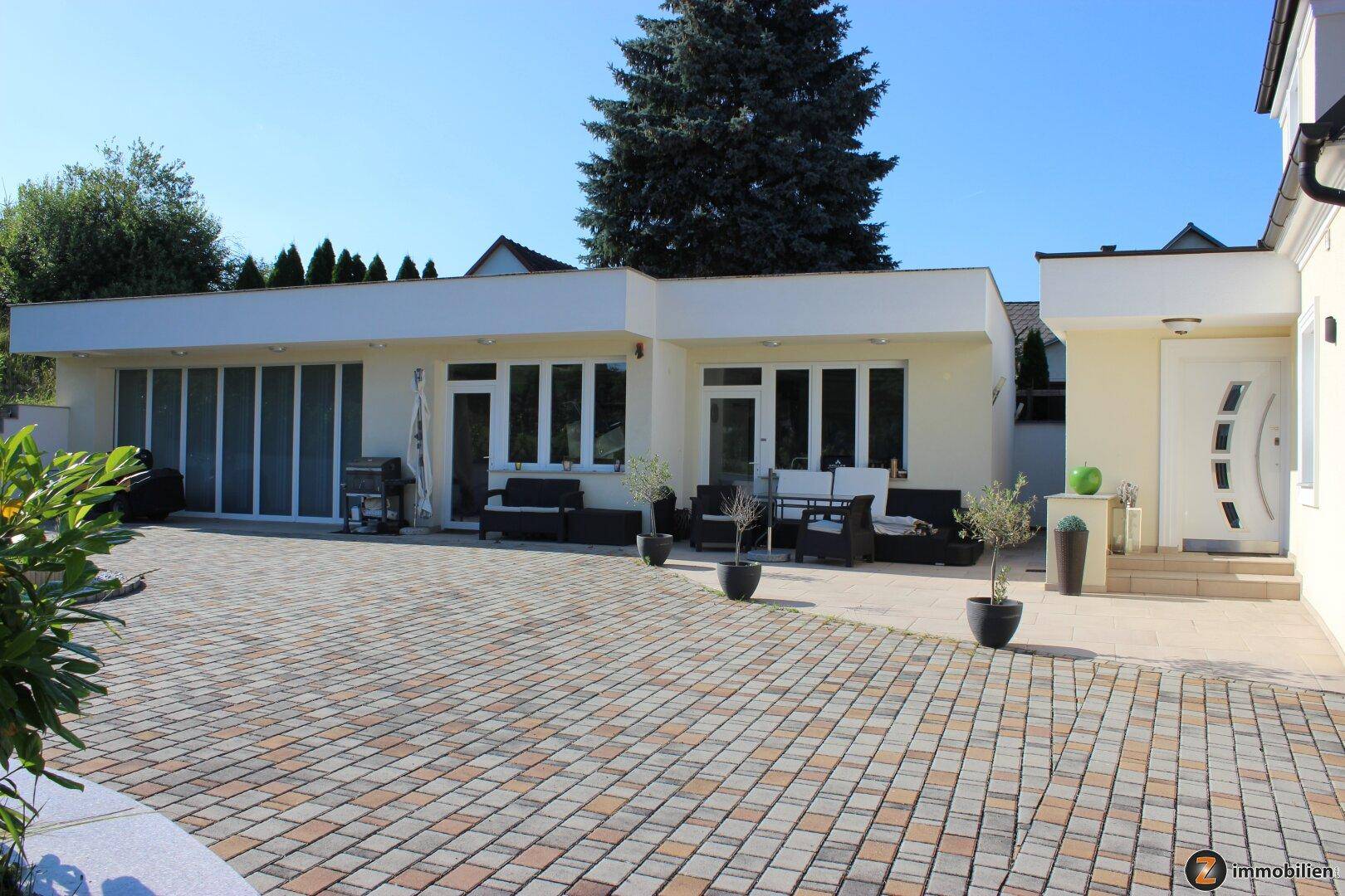 Großzügige gepflasterte Terrasse mit Sitzgelegenheiten und Zugang zum Haus.