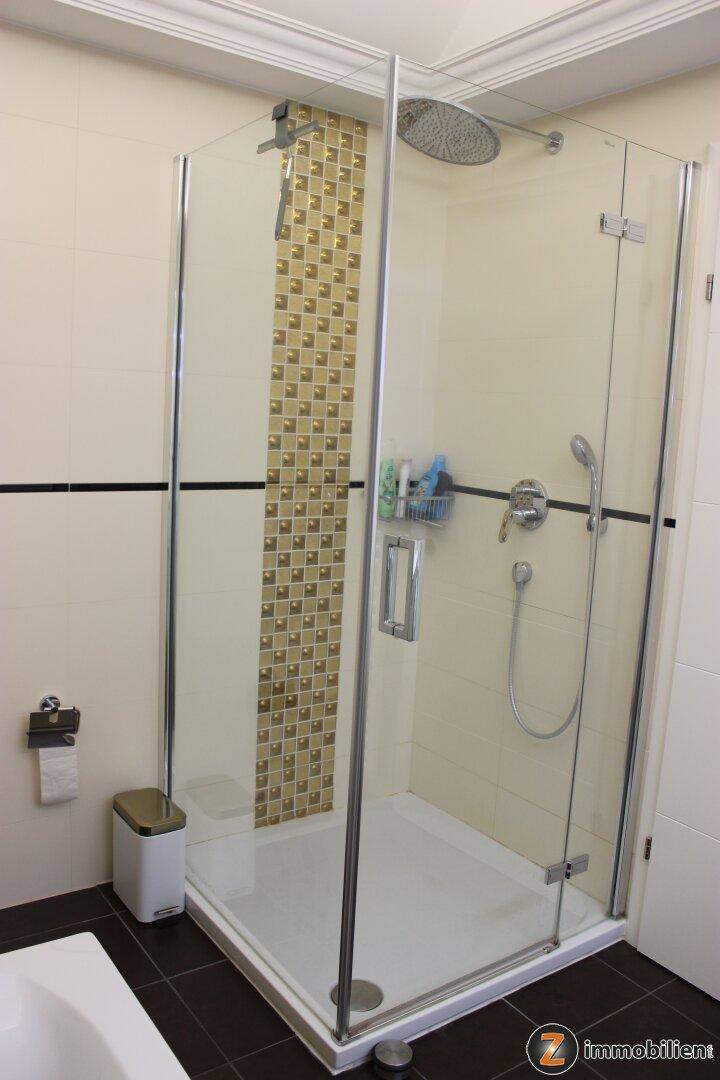 Modernes Badezimmer mit Duschkabine, Regendusche und beigen Fliesen.