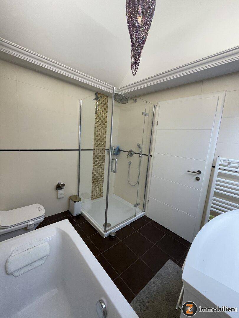 Modernes Badezimmer mit Duschkabine, Toilette und beheiztem Handtuchhalter.