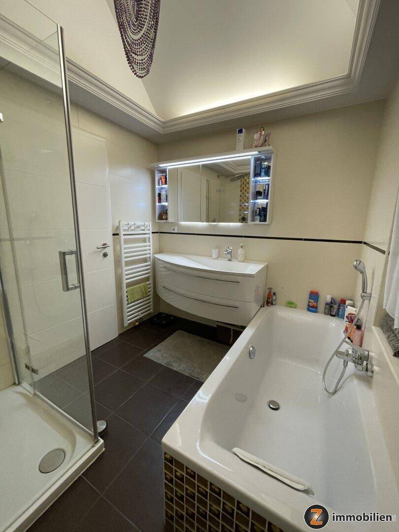 Geräumiges Badezimmer mit Badewanne, Duschkabine, Doppelwaschbecken und Spiegelschrank.