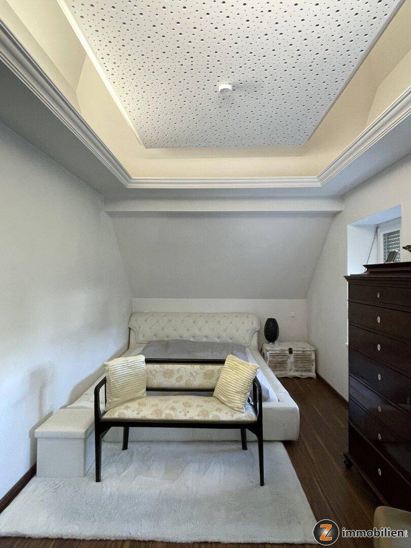 Gemütliches Schlafzimmer im Dachgeschoss mit modernem Bett, Teppich und abgehängter Decke.