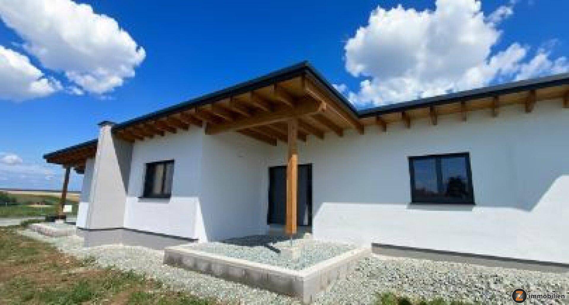 Vorderansicht eines modernen Hauses mit Holzelementen und klarem blauen Himmel.