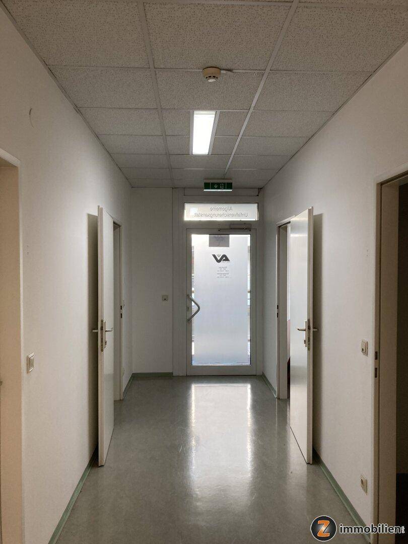 Langer, heller Flur mit mehreren Türen und einem glänzenden Boden, der zu verschiedenen Räumen führt.