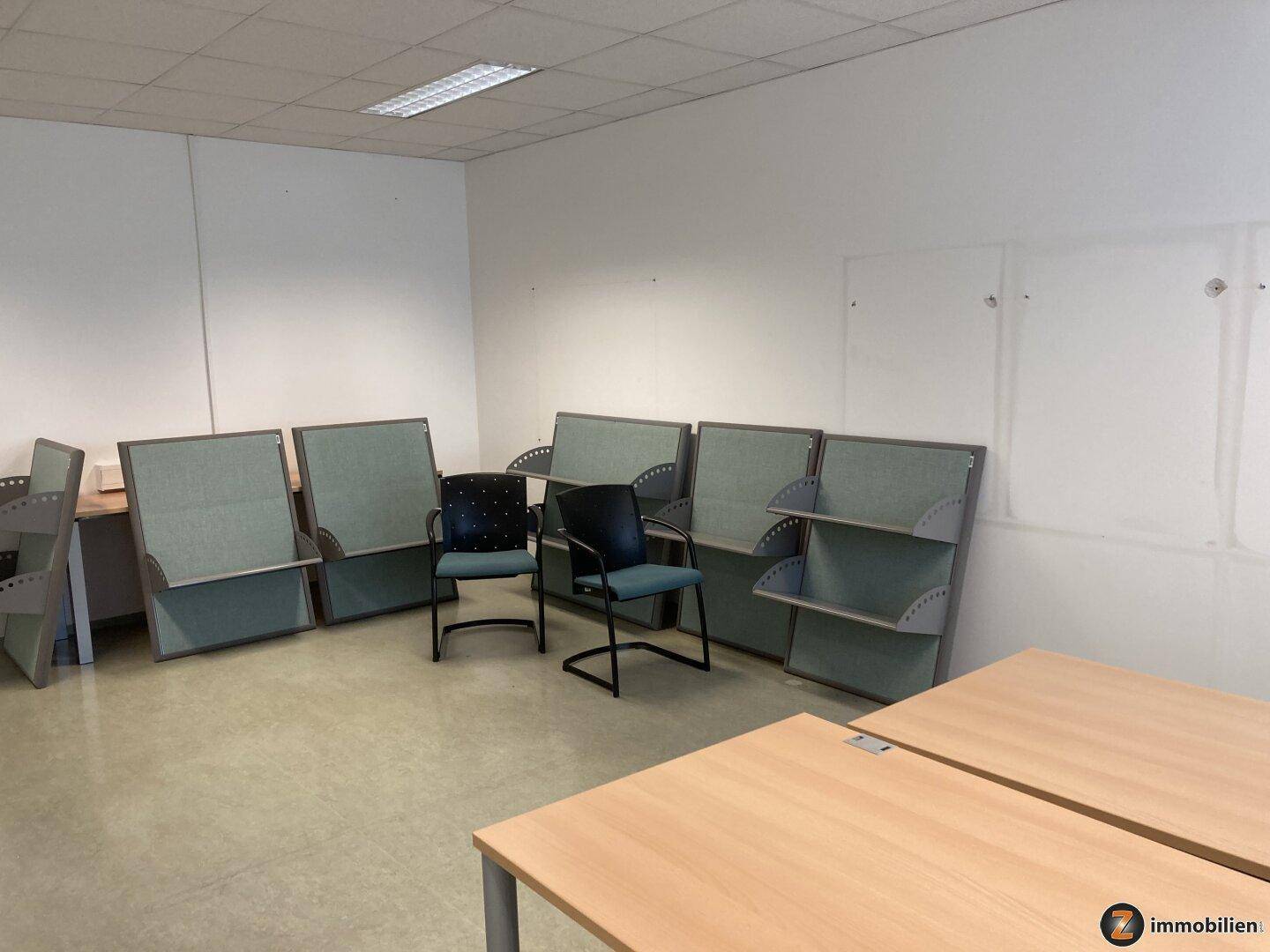 Bürofläche mit mehreren Schreibtischen und Trennwänden, die eine flexible Arbeitsumgebung ermöglichen.