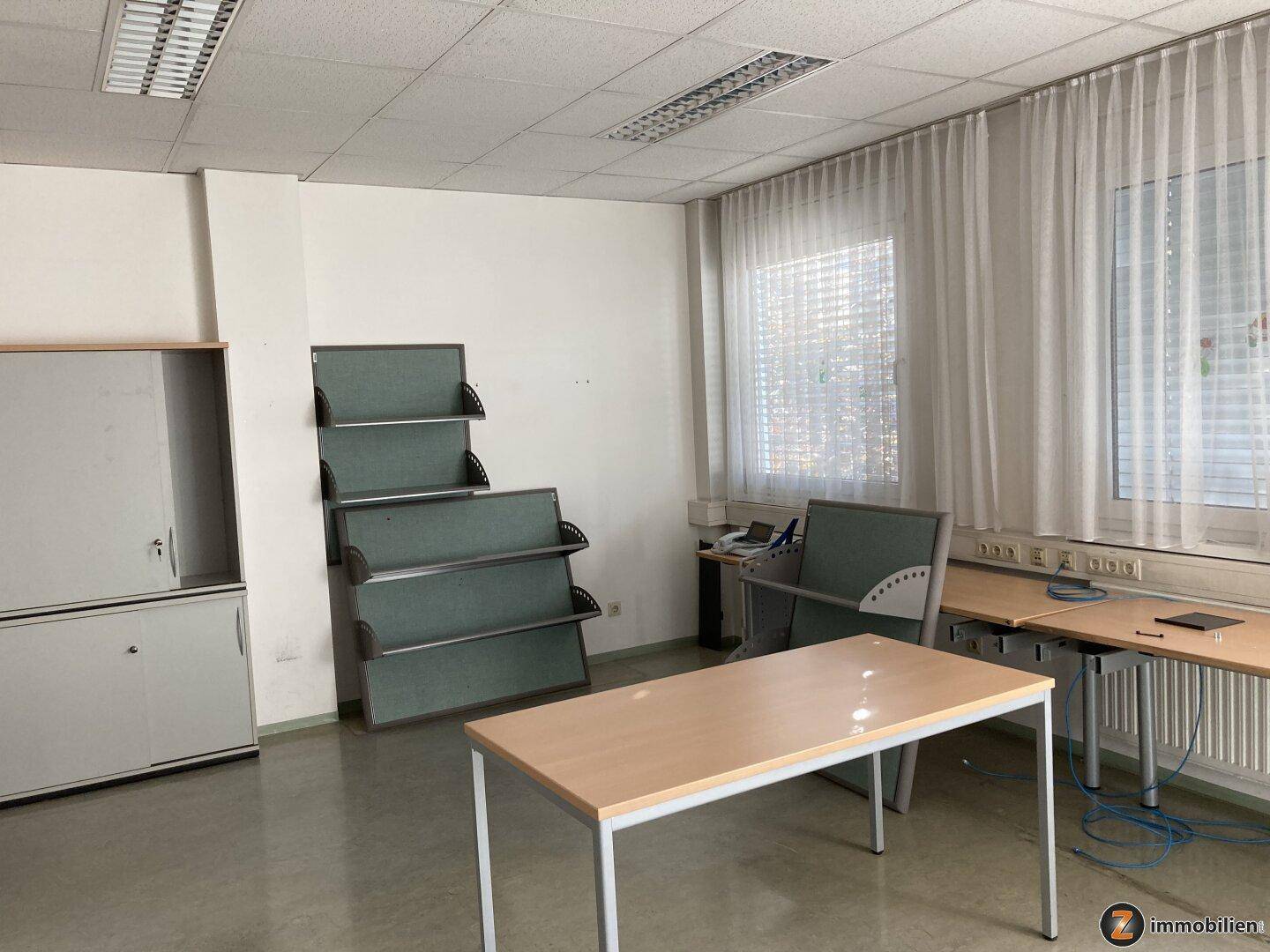 Geräumiges Büro mit Schreibtischen, Schränken und Trennwänden, bietet eine funktionale Arbeitsumgebung.