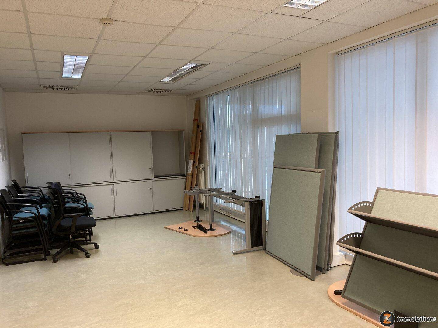 Großes Büro mit Schränken, Stühlen und Trennwänden, bietet viel Platz für verschiedene Arbeitsbereiche.