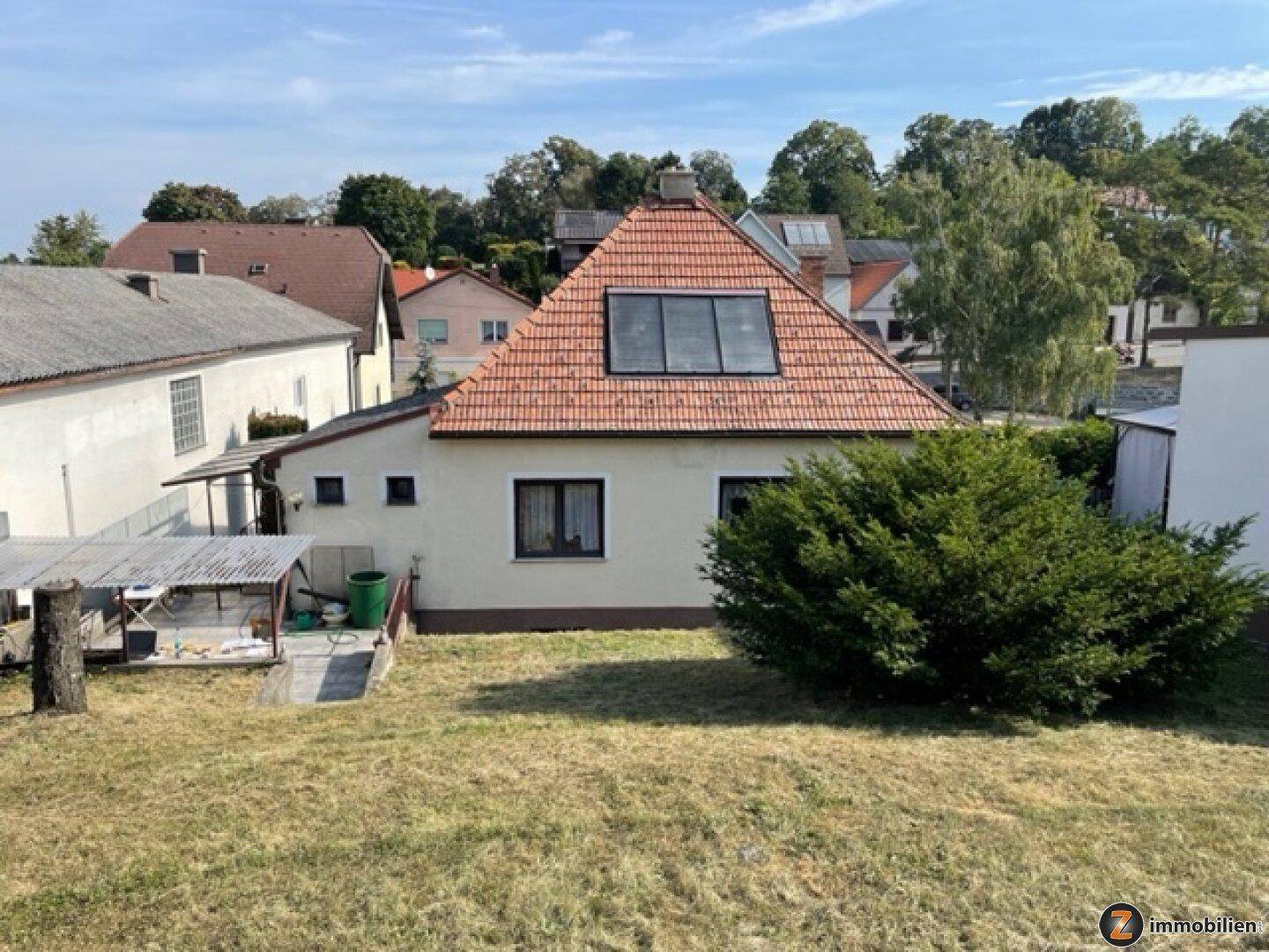 Rückansicht des Hauses mit Garten, Schuppen und Dachfenstern auf dem Ziegeldach.
