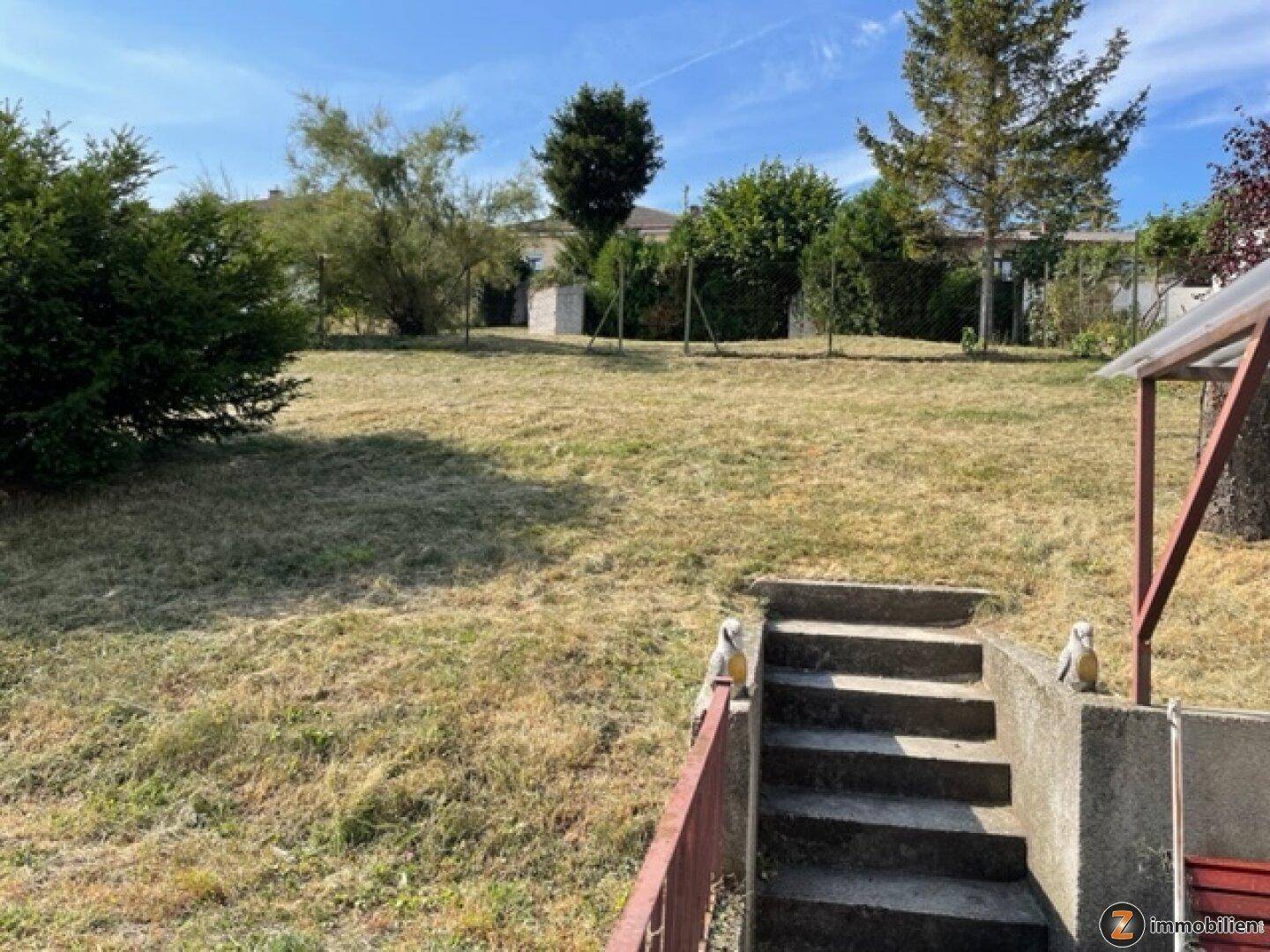 Großer, sonniger Gartenbereich mit Rasenfläche und Steintreppe, umgeben von Bäumen.