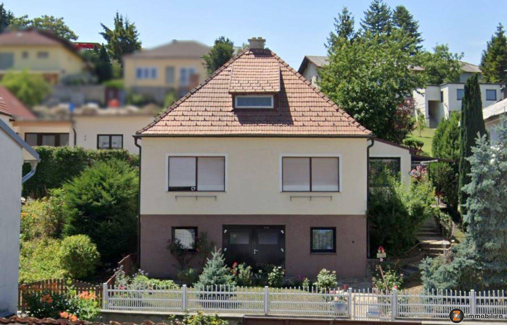 Vorderansicht des Einfamilienhauses mit gepflegtem Vorgarten, Zaun und Satteldach.