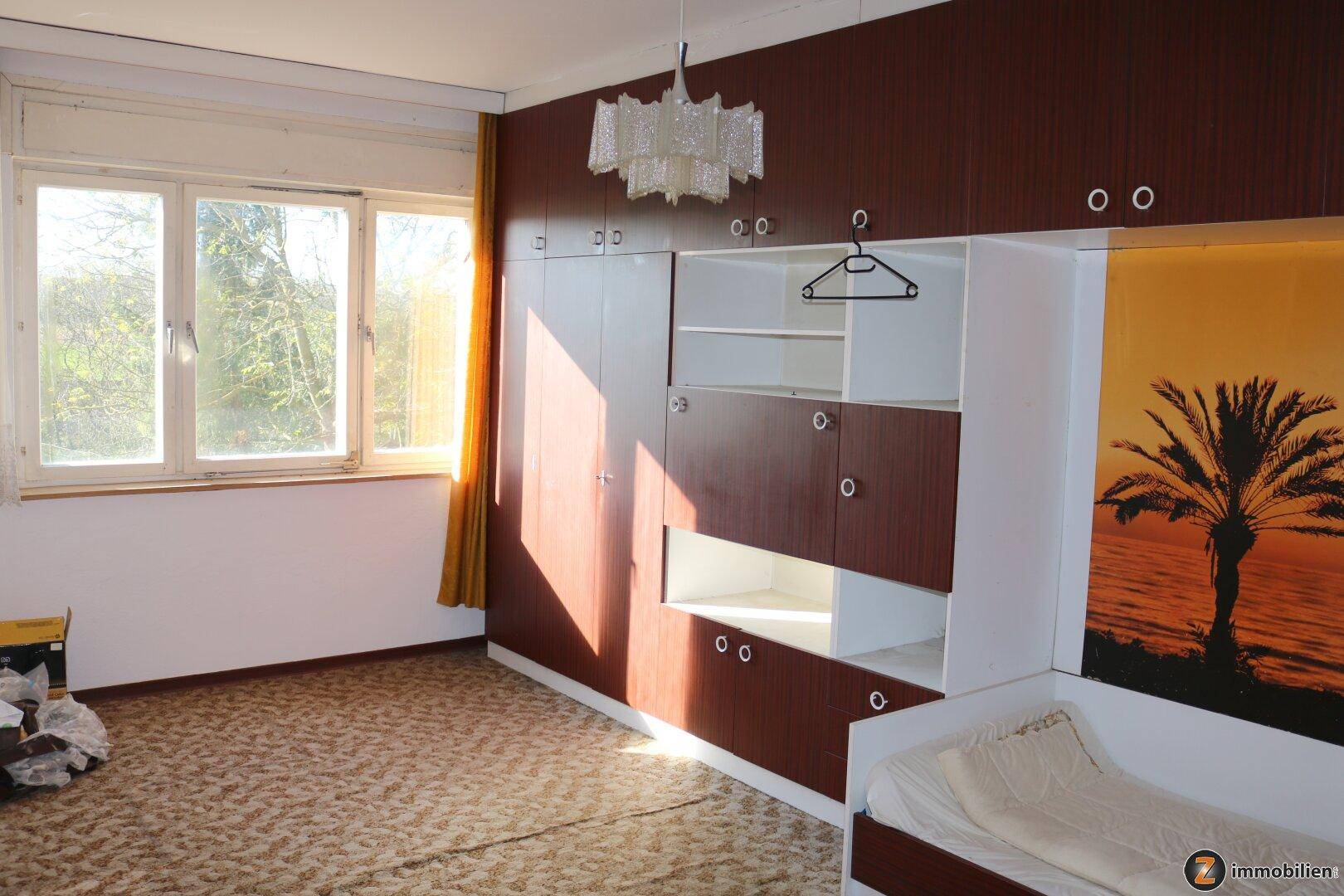 Schlafzimmer mit großen Einbauschränken, Teppichboden und viel natürlichem Licht.