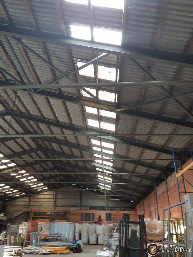 Blick auf die Dachkonstruktion einer Lagerhalle mit vielen Oberlichtern und sichtbaren Metallträgern.