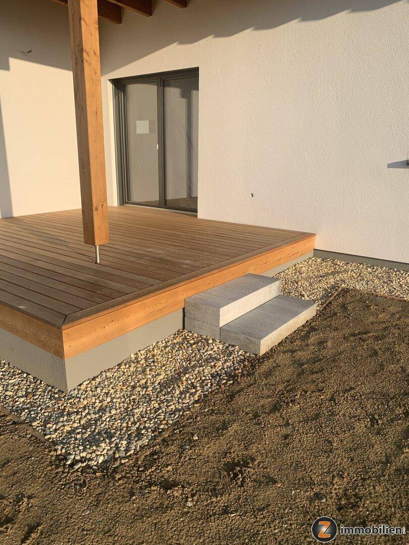 Neue Holzterrasse mit Stufen und Zugang zum Haus, umgeben von Kies und Erde.