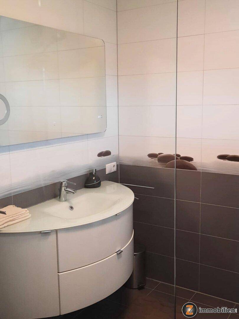 Modernes Badezimmer mit elegantem Waschbecken, Spiegel und zweifarbigen Fliesen.