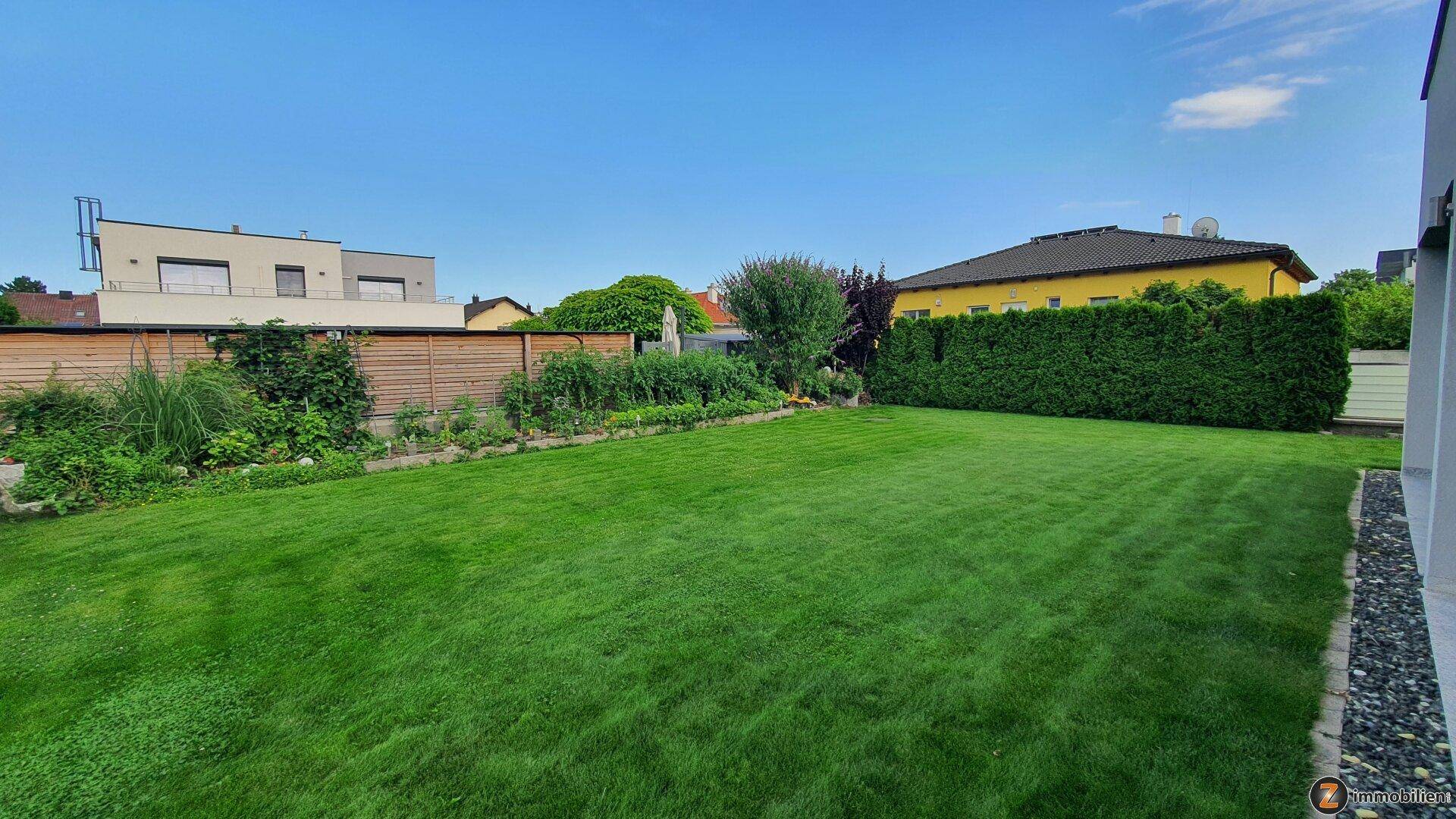 Weitläufiger, gepflegter Garten mit großer Rasenfläche und umgebender Bepflanzung.