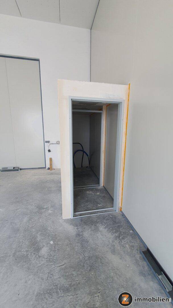 Nahaufnahme einer unfertigen Türöffnung in einem Gewerberaum mit sichtbaren Installationsrohren.