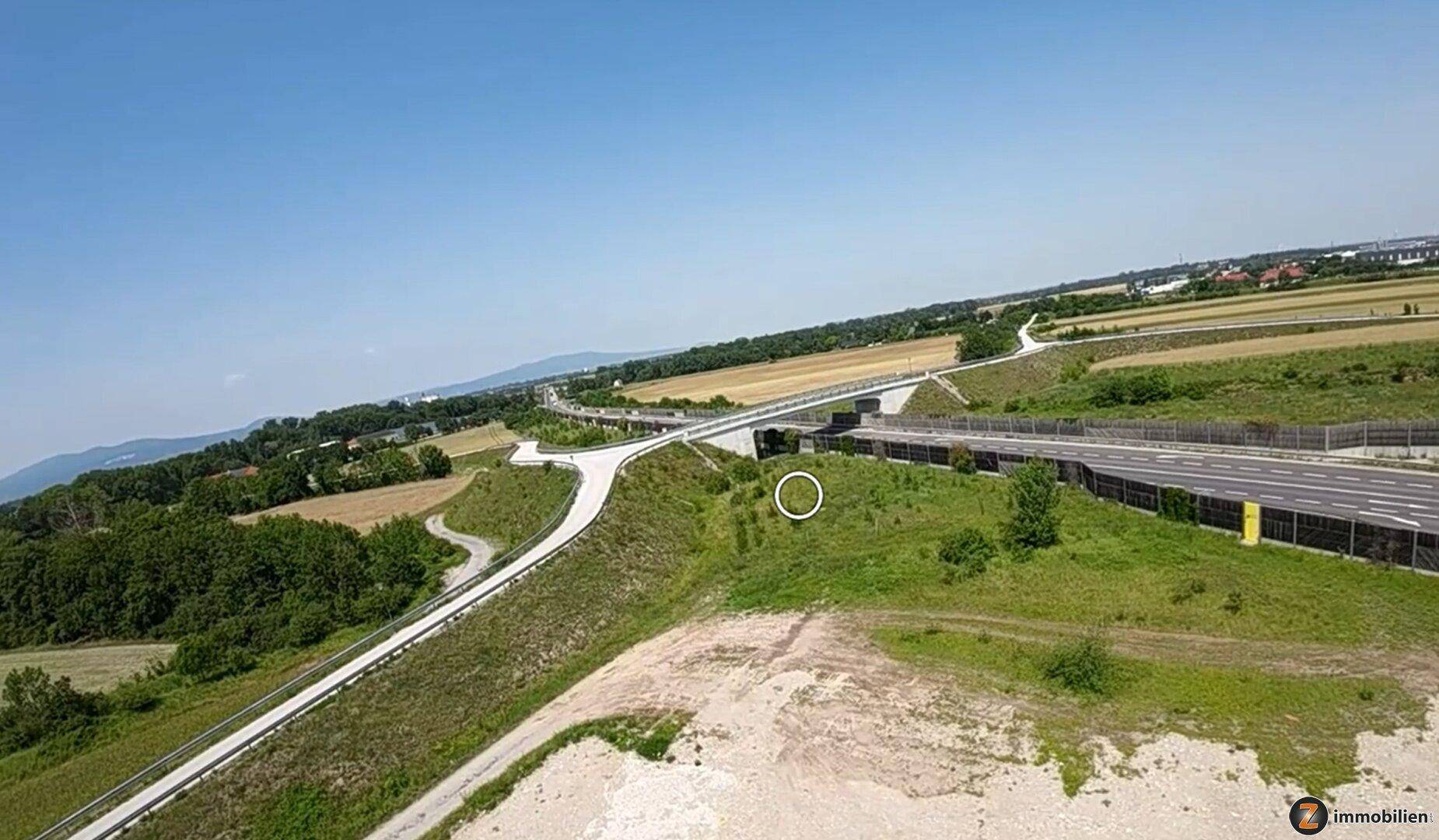 Luftaufnahme einer ländlichen Landschaft mit Straßen, Feldern und einer Autobahn unter blauem Himmel.