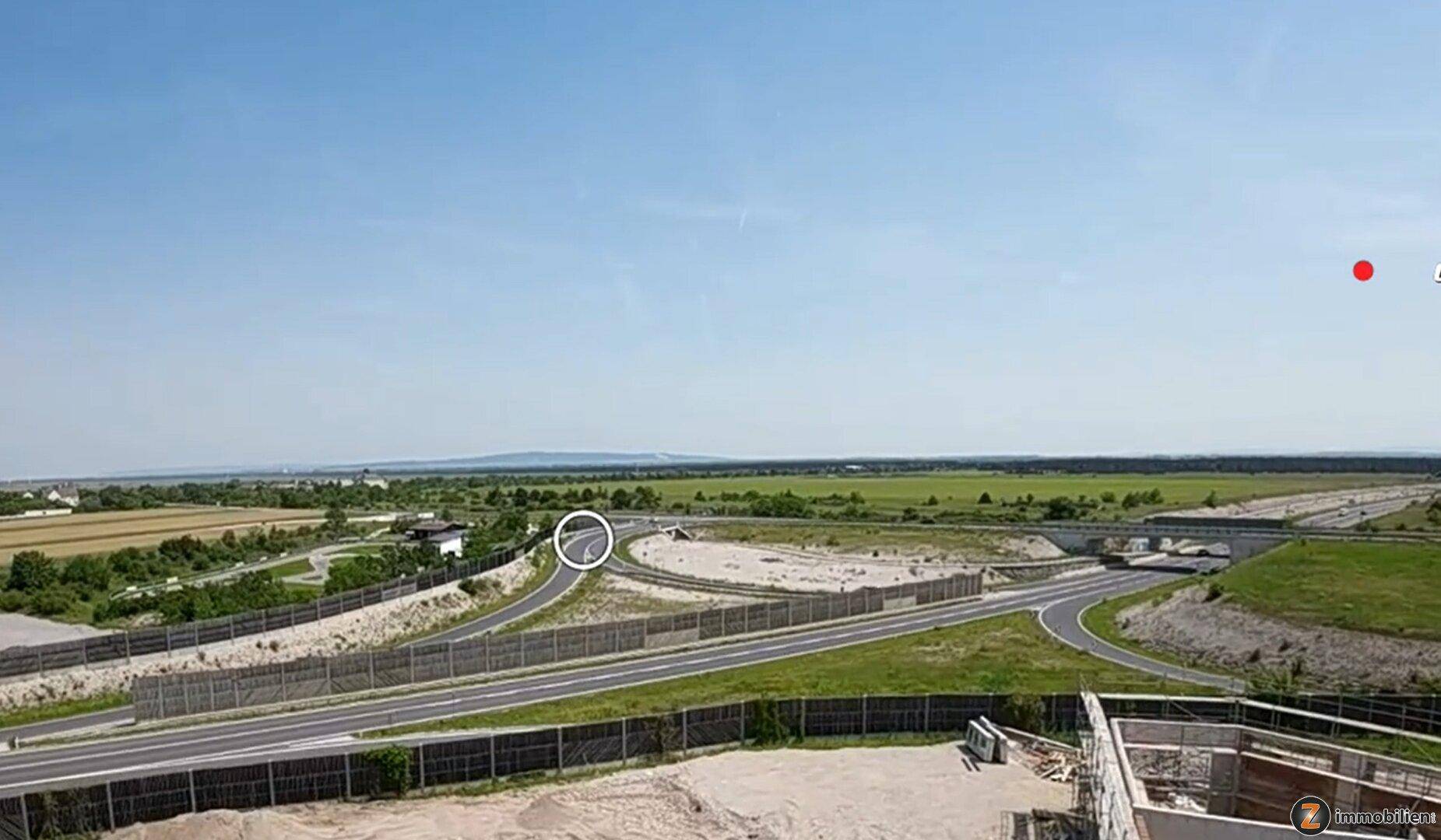 Luftaufnahme einer Autobahnkreuzung in einer weiten Landschaft mit Feldern und Horizont.