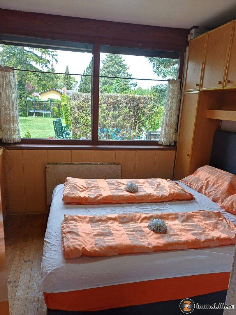 Schlafzimmer mit Doppelbett, Einbauschränken und großem Fenster zum Garten.