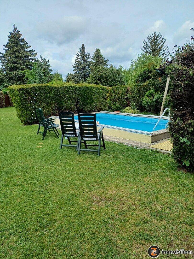 Gepflegter Garten mit eingelassenem Swimmingpool und umgebender Hecke.
