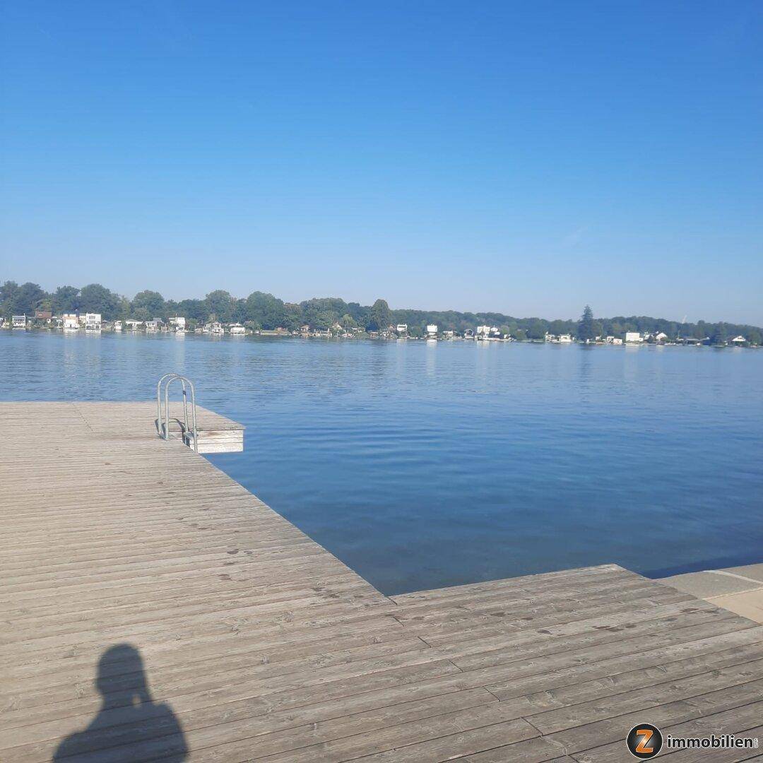 Weitläufiger Holzsteg am See mit weitem Blick über das ruhige Wasser.