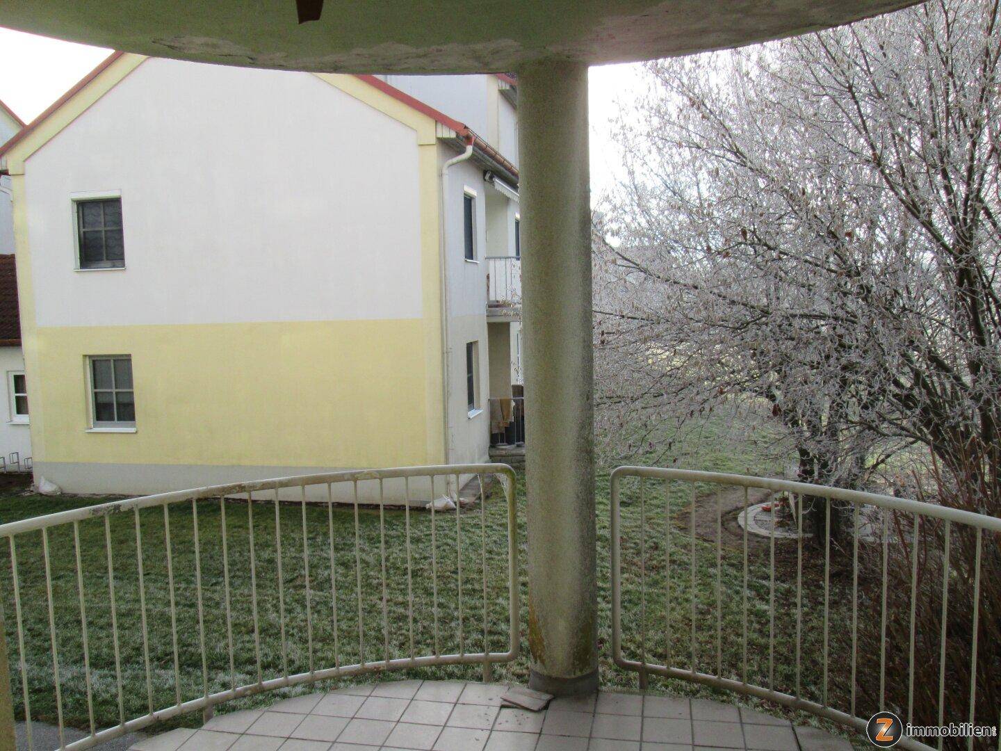 Blick vom Balkon auf das Gebäude und den Gartenbereich im winterlichen Zustand.