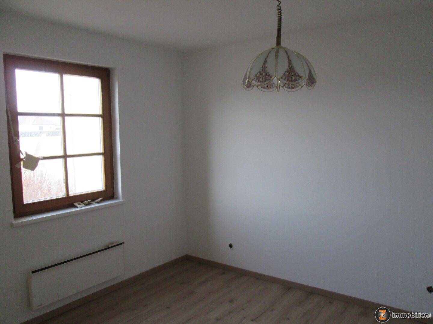 Helles Schlafzimmer mit Laminatboden und einem großen Fenster für viel Tageslicht.