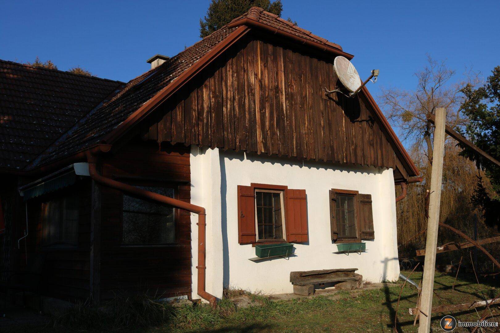 Seitenansicht des Landhauses mit traditionellen Fensterläden und Satellitenschüssel.