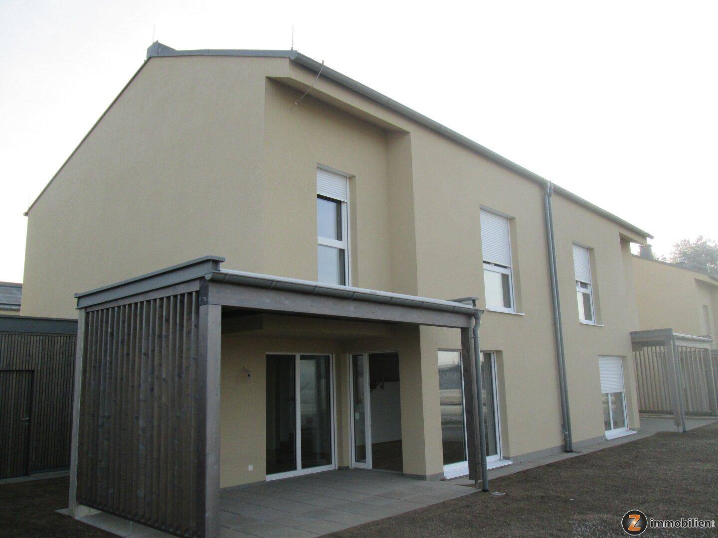 Leerer Raum mit weiß gestrichenen Wänden, Holzboden und einem Fenster mit Rollladen.