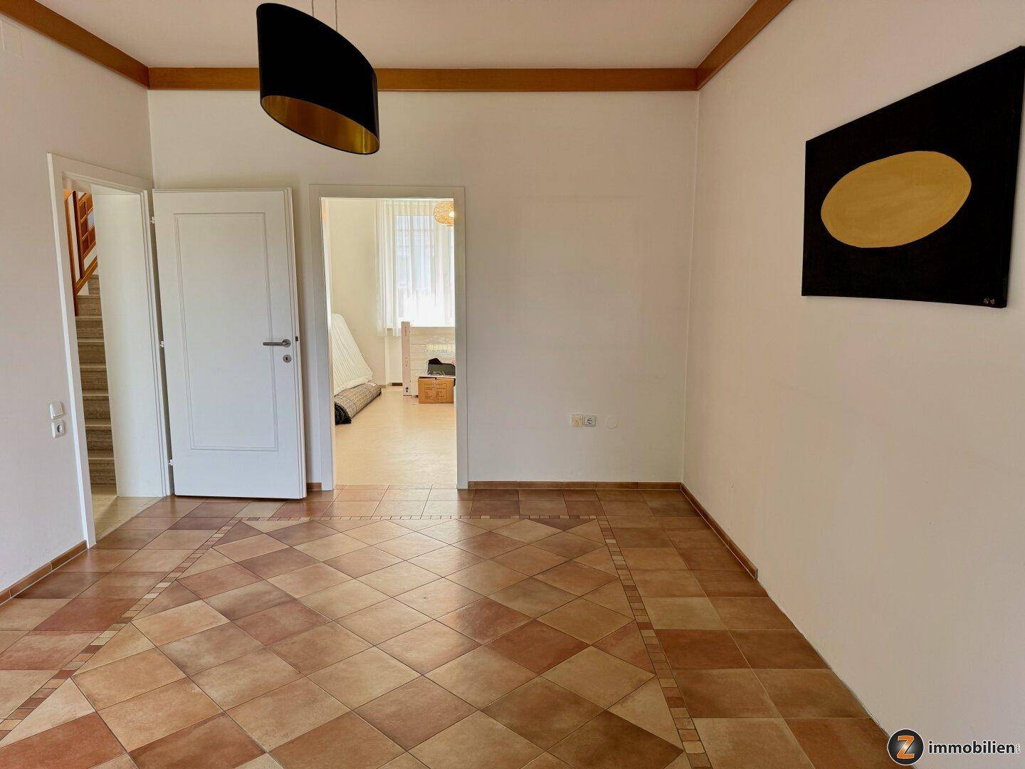Eingangsbereich mit Terrakottafliesen und Zugang zu weiteren Räumen und Treppe.
