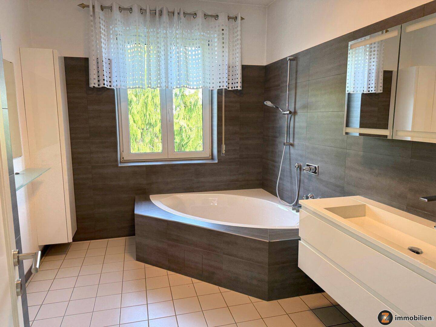Modernes Badezimmer mit Eckbadewanne, Waschtisch und Fenster.