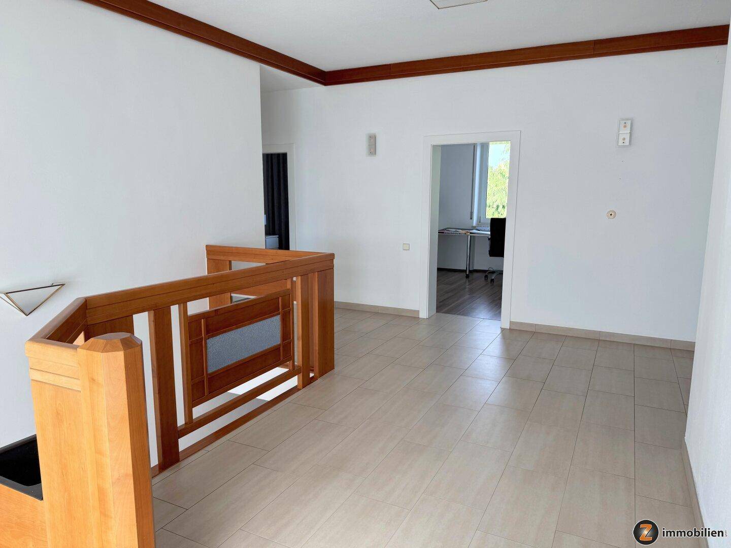 Offener Flurbereich im Obergeschoss mit Holzgeländer und Blick in ein weiteres Zimmer.