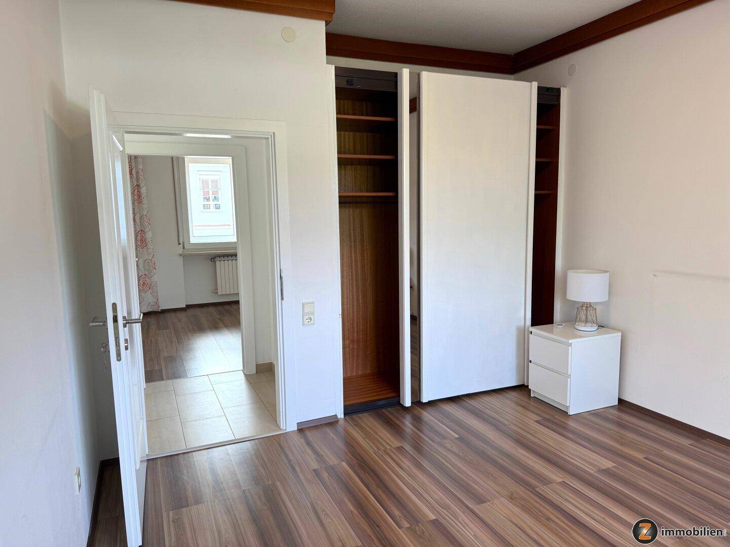 Schlafzimmer mit Laminatboden und praktischem Einbauschrank.