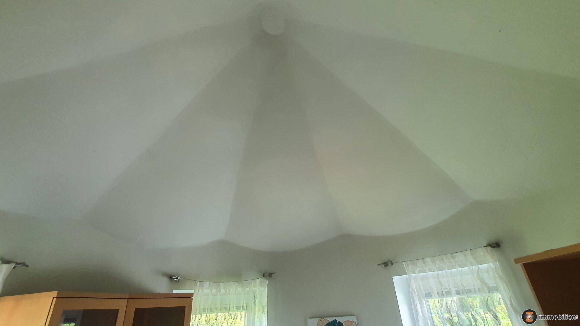Detailaufnahme einer ungewöhnlichen, wellenförmigen Deckenkonstruktion in einem Innenraum.
