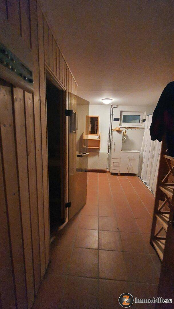 Kellerbereich mit Zugang zu einer Sauna, Fliesenboden und einem Fenster für Belüftung.