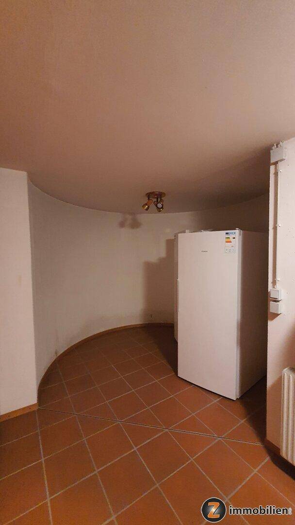 Kellerraum mit Fliesenboden und einem großen Gefrierschrank, ideal als Vorratskammer.