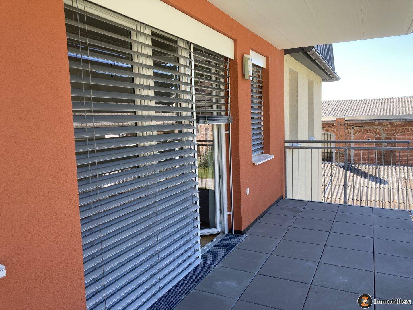 Heller Balkon mit Fliesenboden und Jalousien, bietet einen Blick auf die Umgebung.
