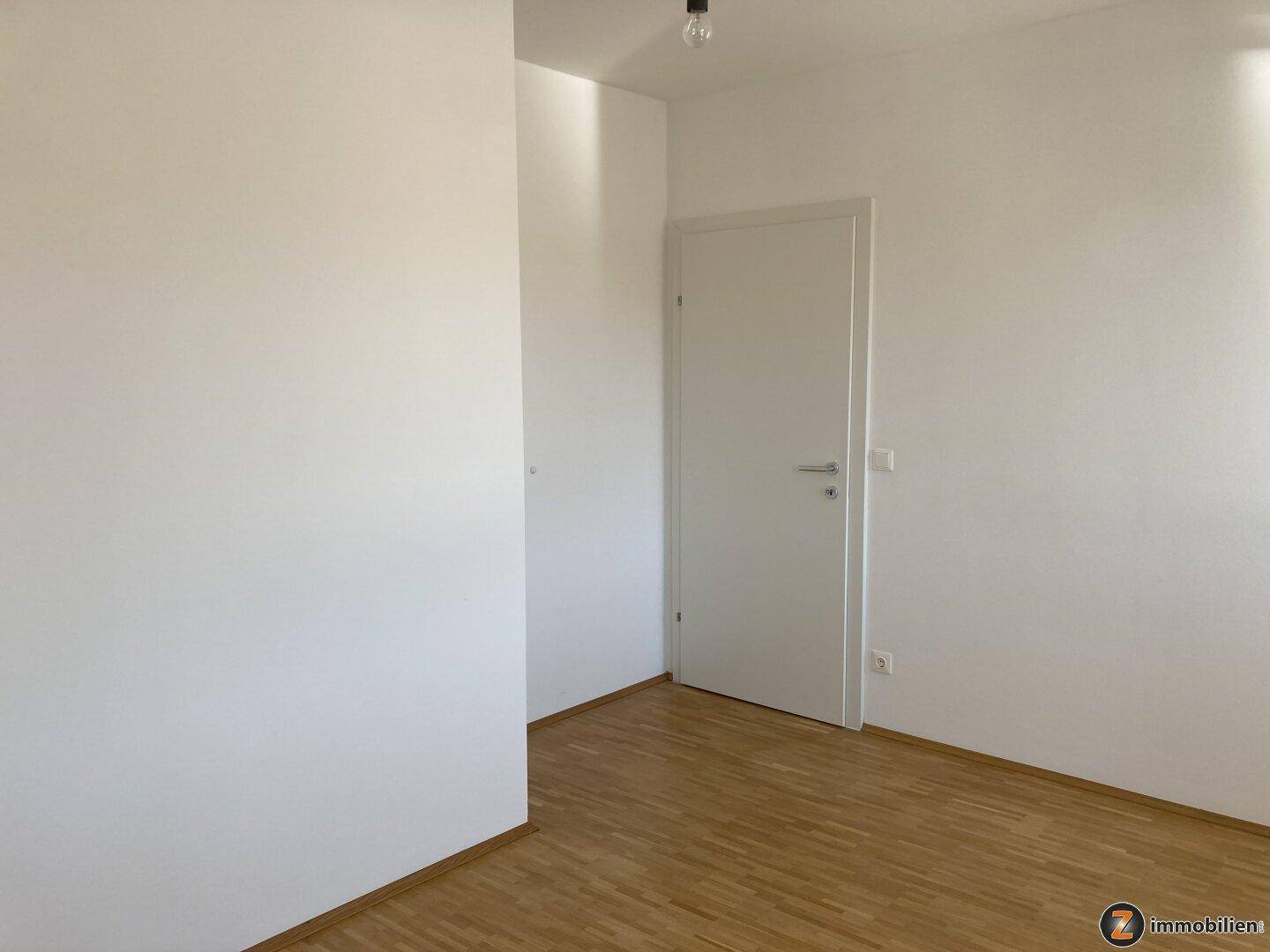 Helles Zimmer mit Parkettboden und weiß gestrichenen Wänden, ideal als Schlafzimmer.