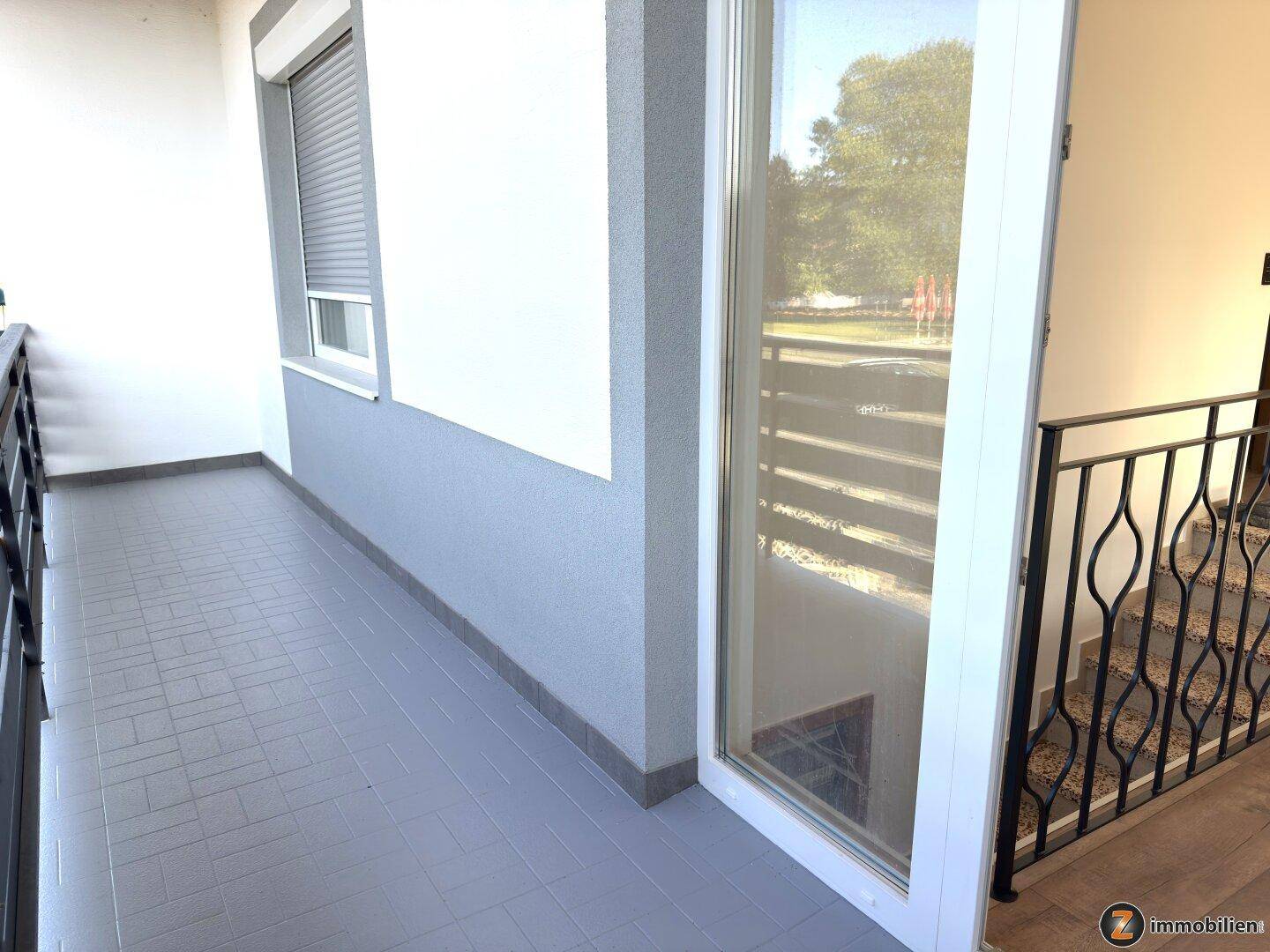 Balkon mit modernem Geländer und Blick auf die Umgebung, zugänglich vom Innenbereich.