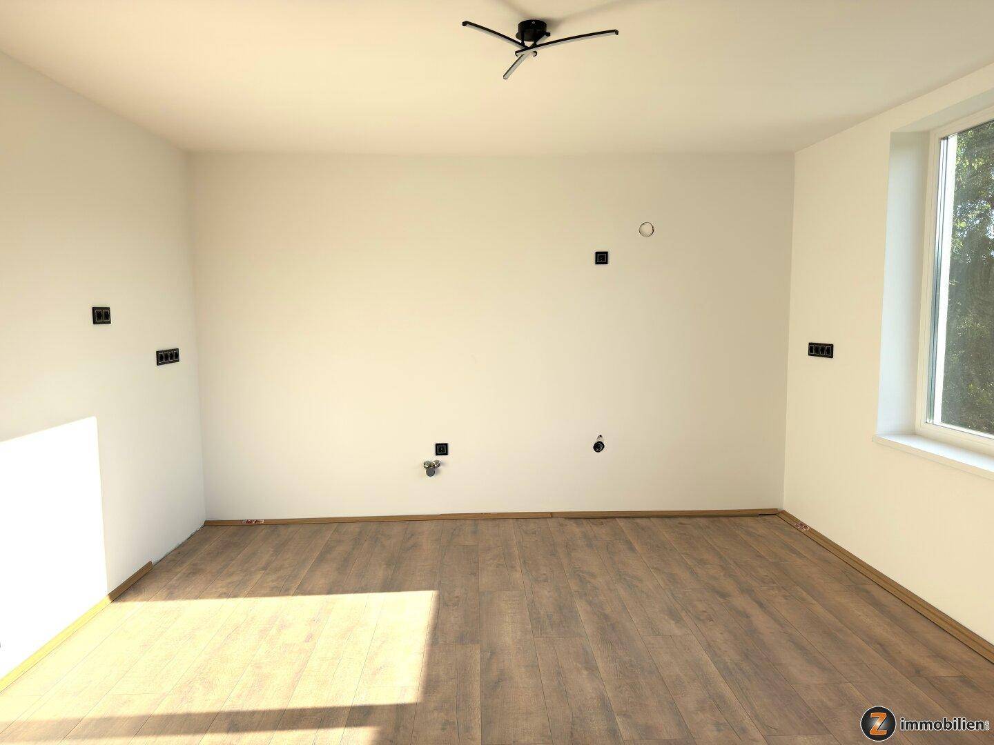 Geräumiges Schlafzimmer mit Laminatboden und großen Fenstern, bereit zur Einrichtung.